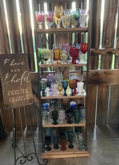 a display case filled with lots of different colored glasses and wine glasses next to a sign