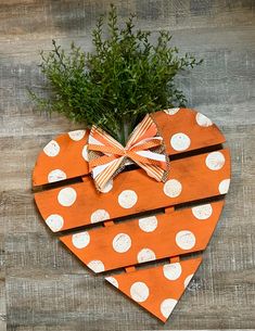 an orange heart with white polka dots and a bow hanging on the side, made out of wood planks