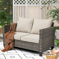 a wicker couch sitting on top of a tiled floor next to a potted plant