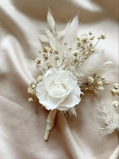 a white flower and some feathers on a bed