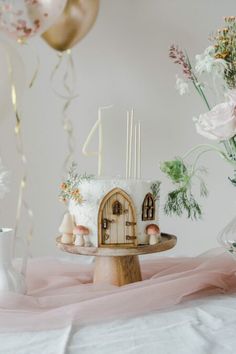 a cake with mushrooms on it sitting on a table next to some balloons and flowers