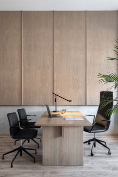 an office with wooden paneling and black leather chairs in front of a large window