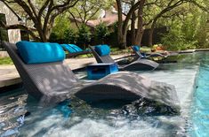 two lounge chairs sitting in the middle of a swimming pool