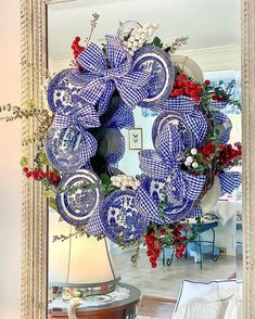 a blue and white wreath with red flowers on it in front of a large mirror