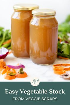 two mason jars filled with vegetable stock sitting on top of a table next to vegetables