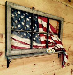 an american flag painted on the side of a window with flowers in front of it