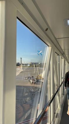 a man walking down an escalator next to a window with planes in the background