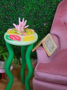 a pink chair sitting next to a green table