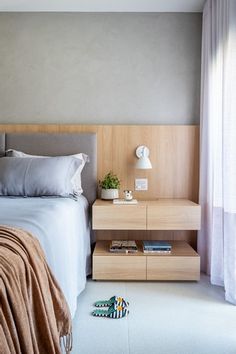 a bed sitting next to a night stand with a lamp on it's side