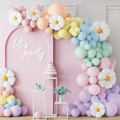 a pink backdrop with balloons and flowers on the wall is decorated in pastel colors