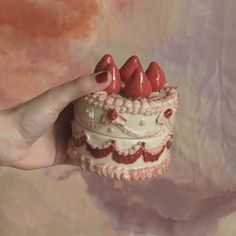 a hand holding a small cake with red hearts on it's top and bottom