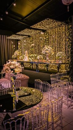 a room filled with lots of chairs and tables covered in yellow string lights next to a banquet table