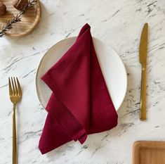 a white plate topped with a red napkin next to a knife and fork on top of a table