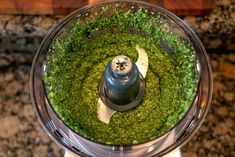 a food processor filled with green stuff on top of a counter