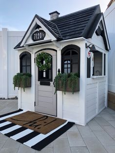 a small white house with plants on the front door and numbers on the top window sill