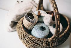 a basket filled with balls of yarn next to a stuffed animal on a wall behind it