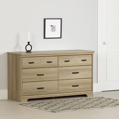 a wooden dresser sitting on top of a rug in a living room next to a white wall