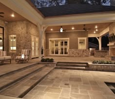 an outdoor living area with stone steps leading up to the front door and patio at night