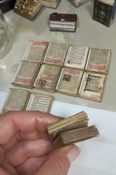 a person is holding several old books in their hand and they are sitting on the table