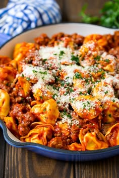 a bowl filled with pasta covered in sauce and parmesan cheese, on top of a wooden table