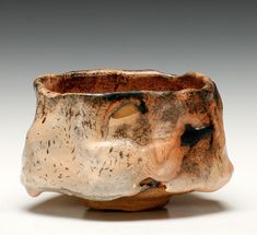 a brown and black ceramic bowl on a white surface with an animal's head in the center