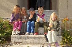 four children are sitting on the steps eating ice cream and looking up at the camera