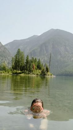 a person swimming in the water with mountains in the background