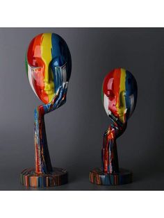 two colorful sculptures sitting on top of each other in front of a gray background,