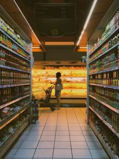 a woman standing in the aisle of a grocery store filled with lots of food and drinks