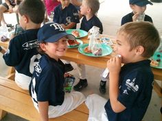 several children sitting at a picnic table eating food