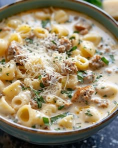 a bowl of pasta soup with sausage and parmesan cheese on top, ready to be eaten