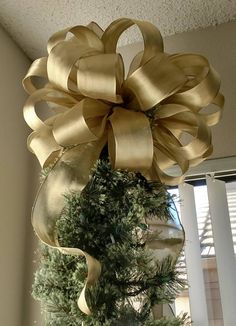 a large gold bow hanging from the side of a tree in front of a window