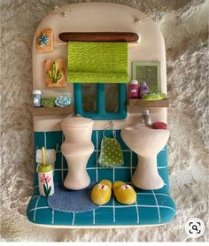 a dollhouse bathroom with toilet, sink, and other items on the counter top