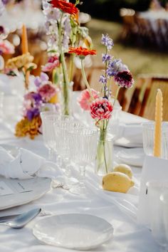 the table is set with white plates, silverware and vases filled with flowers