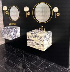 two sinks and mirrors in a bathroom with black marble flooring, gold accents on the wall