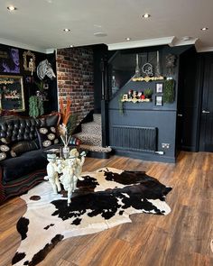 a living room filled with black furniture and lots of cow hides on the floor