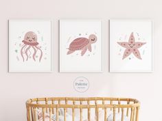 three pink sea animals are hanging on the wall next to a baby's crib