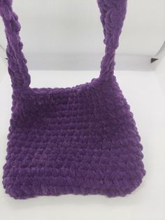 a crocheted purple bag sitting on top of a white table