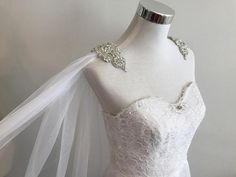 a white wedding dress on a mannequin with a veil over the bustle