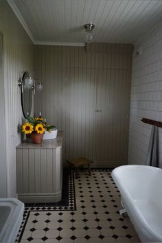 a white bath tub sitting next to a sink in a bathroom under a light fixture