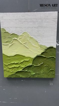 a painting with green and white paint on the side of a gray wall that has mountains in it