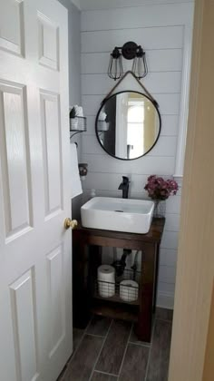 a white sink sitting under a mirror next to a wooden cabinet and wall mounted faucet