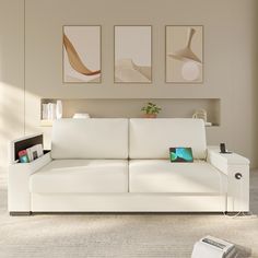 a white couch sitting in a living room under three paintings