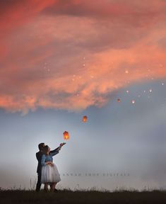 a man and woman are holding lanterns in the sky