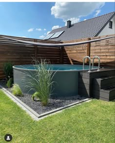 an outdoor hot tub in the middle of a yard with grass and plants around it