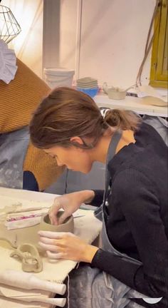 a woman is working on a pottery piece