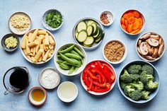 several bowls filled with different types of food on top of a blue tablecloth next to cups and sauces