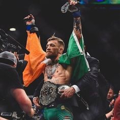 the man is holding his arms in the air while standing next to another man with an irish flag on his shoulders