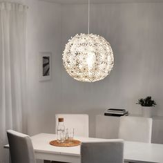 a white dining room table and chairs with a light fixture hanging over it's head