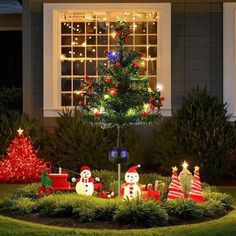 a christmas tree in the middle of a yard with lights on it and snowmen